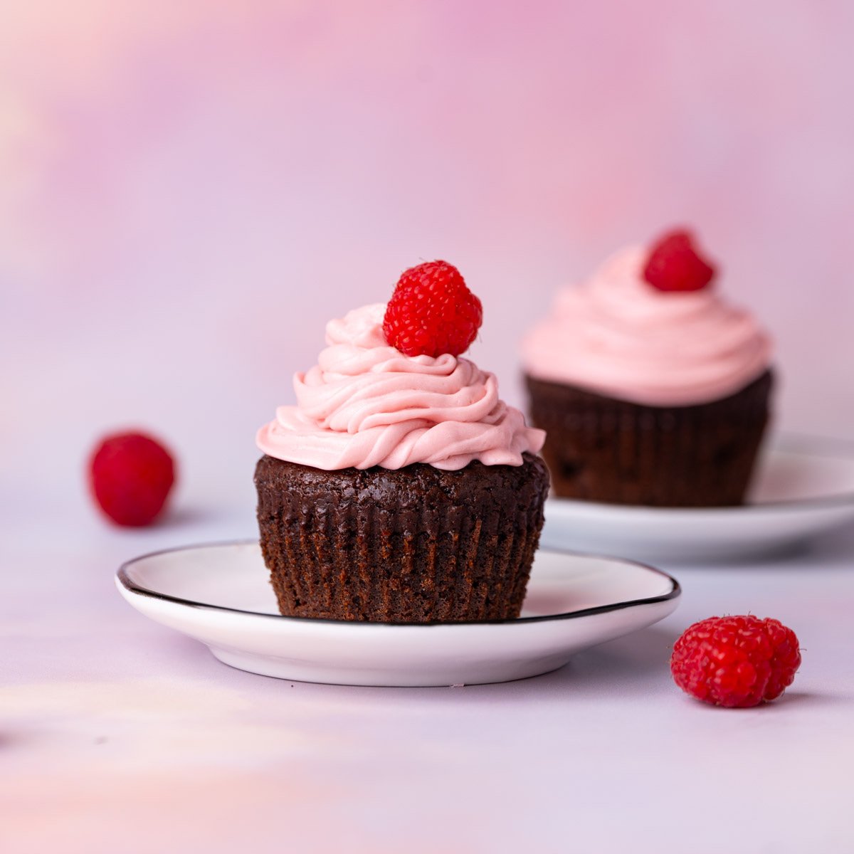Chocolate cupcakes with homemade raspberry buttercream frosting topped with a fresh raspberry.