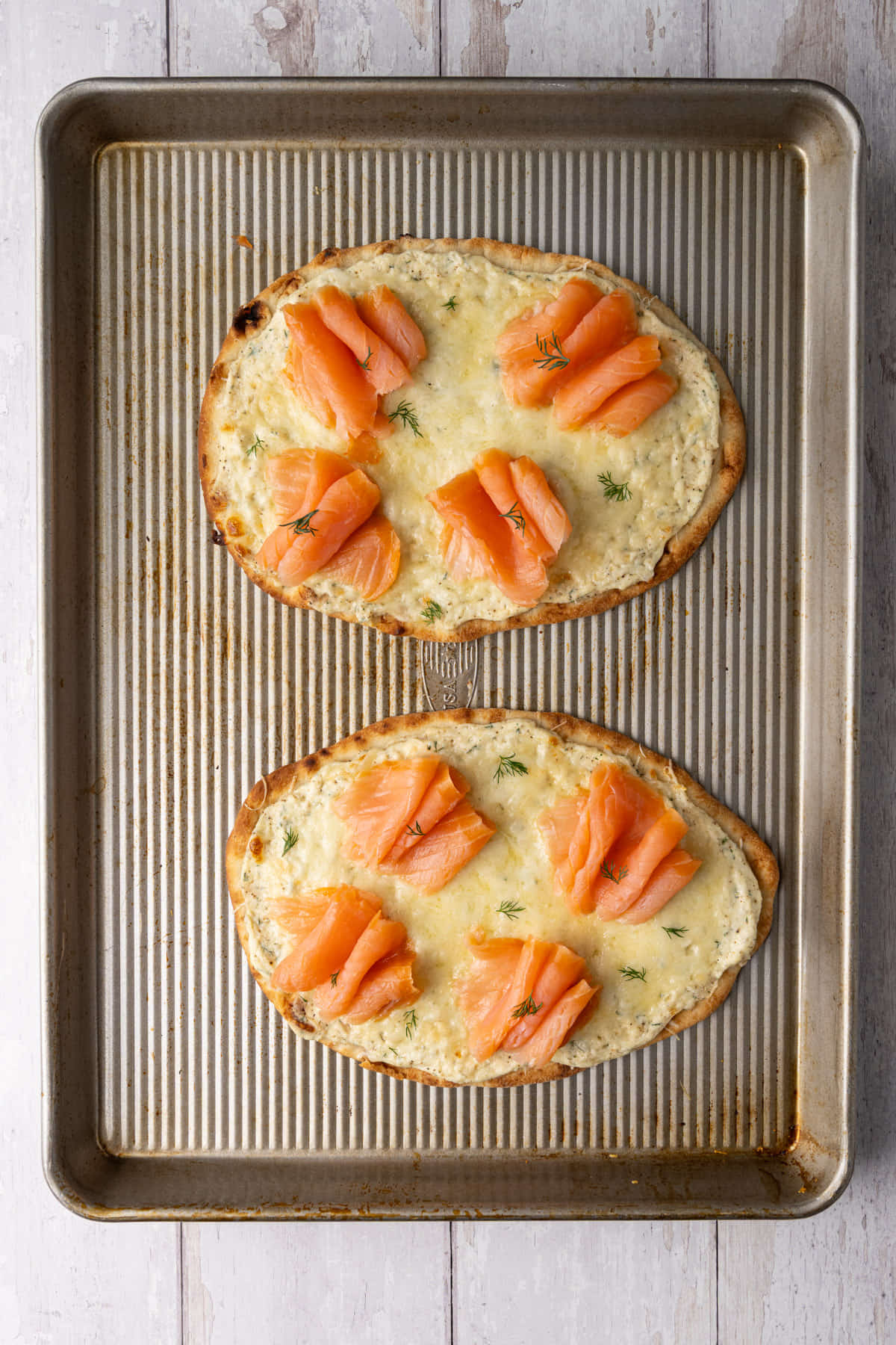 Smoked salmon placed on top of a just-baked cheesy flatbread. 