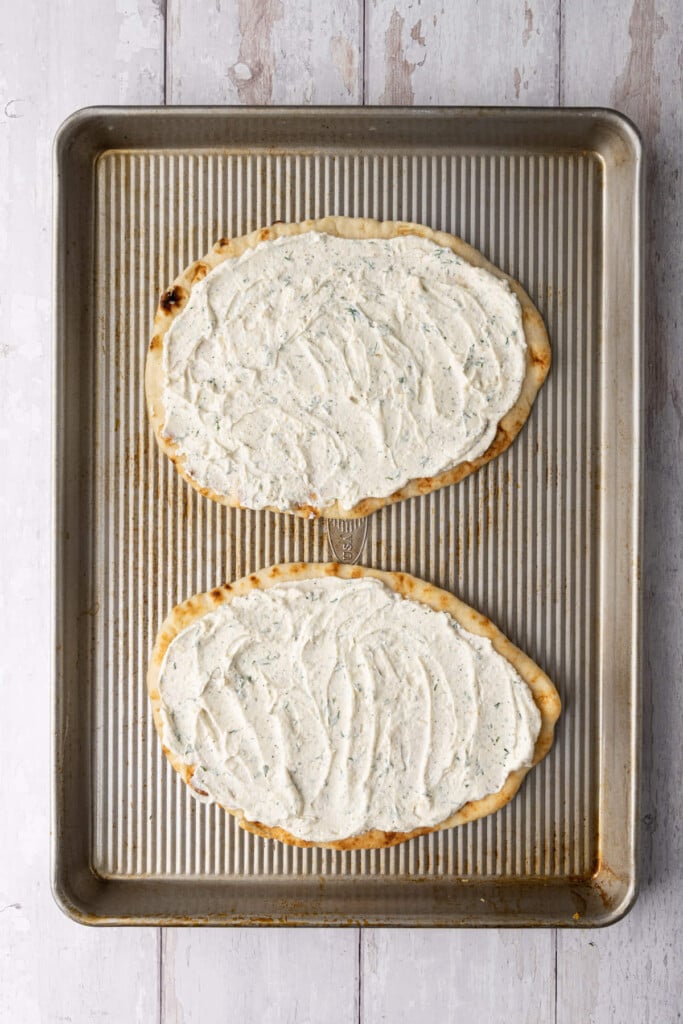 Ricotta, garlic, and dill mixture spread evenly in a generous layer on naan bread. 