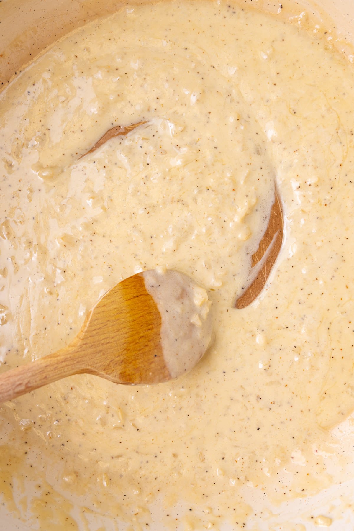 Adding cream to white wine sauce and allowing to thicken.