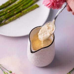 White wine cream sauce dripping off of a spoon into a creamer.