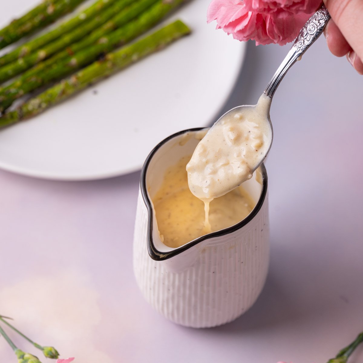 White wine cream sauce dripping off of a spoon into a creamer.