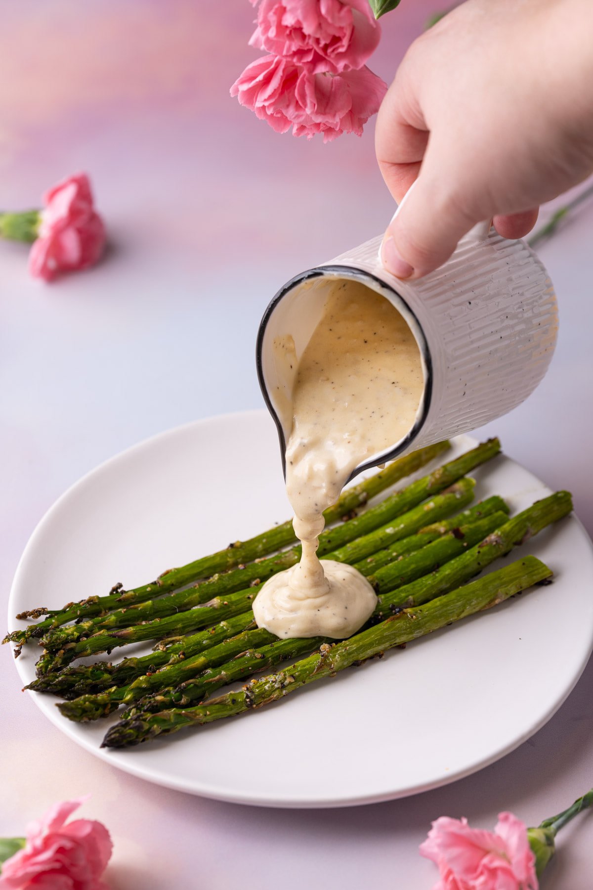 Pouring cream sauce with white wine over roasted asparagus. 
