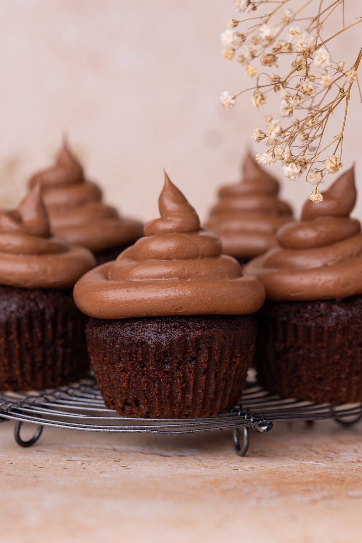Close up of chocolate cupcake with piped on piles of chocolate cream cheese frosting.
