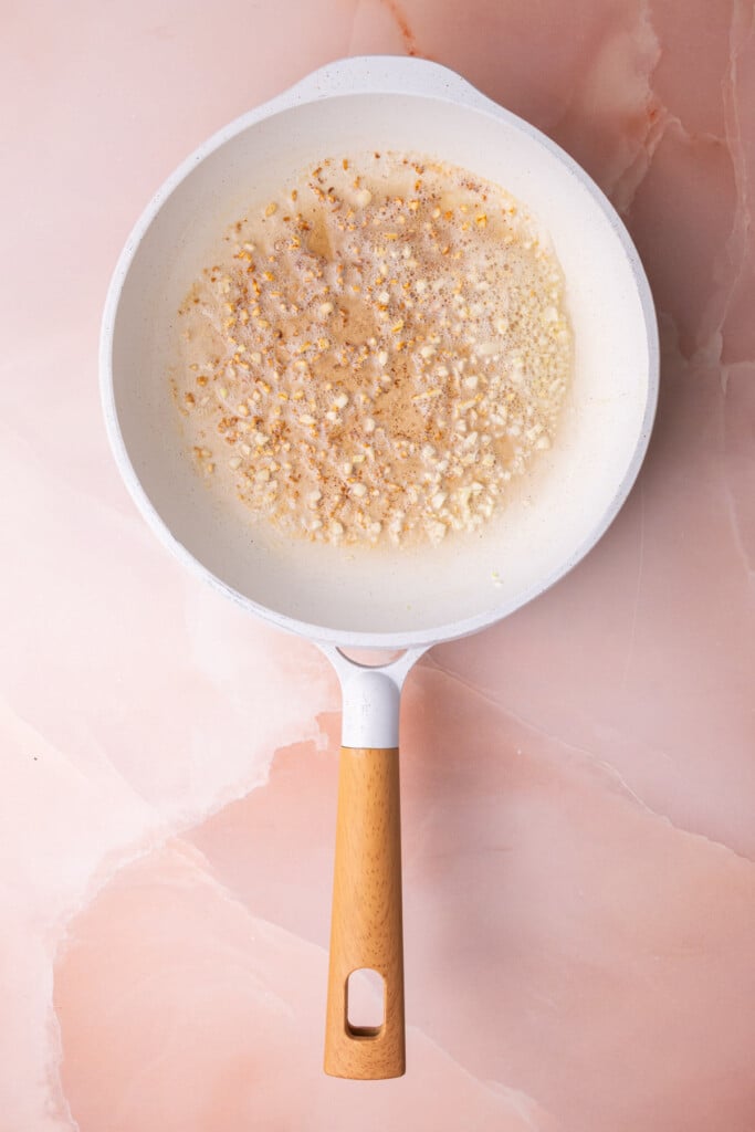 Minced garlic cooking in butter in a frying pan. 