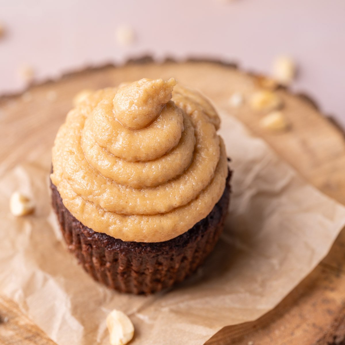 Close up of chocolate cupcake piled high with simple whipped peanut butter and cream cheese frosting.