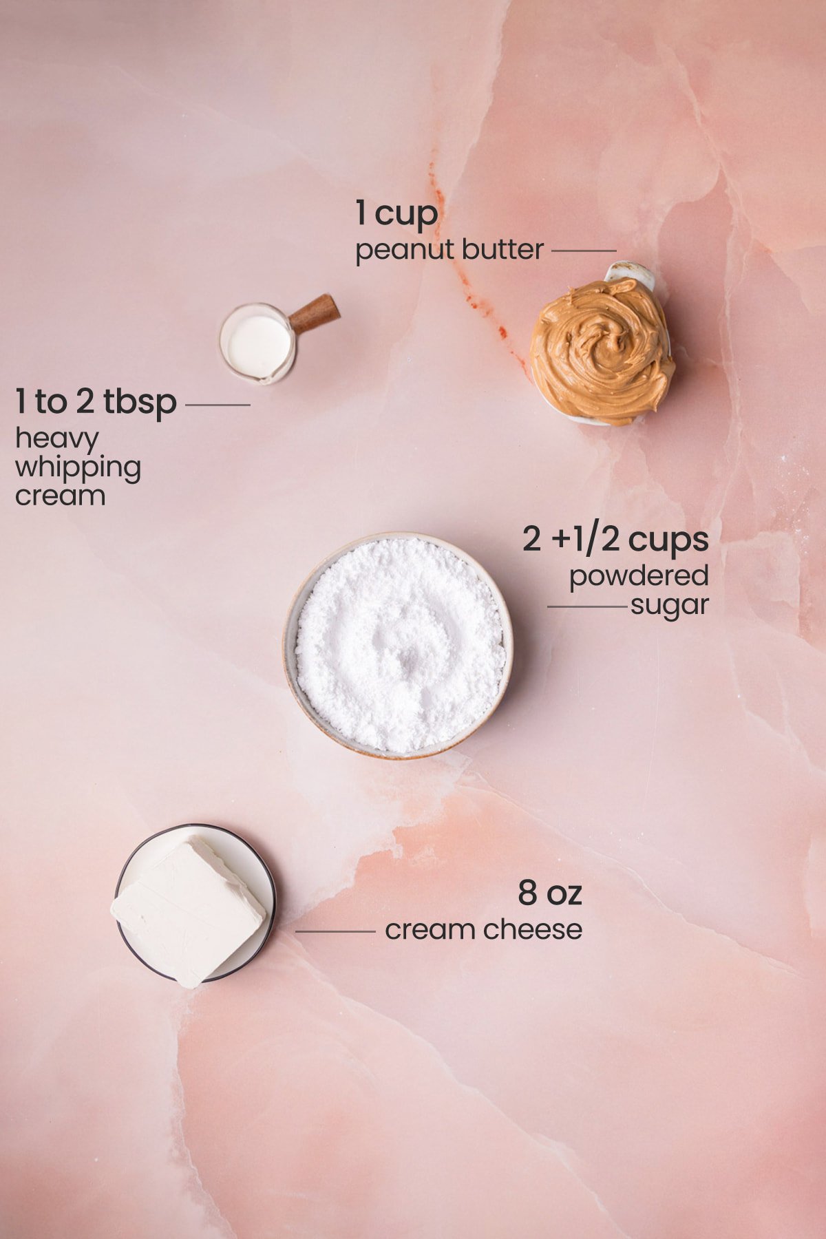 Overhead view of the ingredients needed for peanut butter cream cheese frosting - heavy whipping cream, peanut butter, powdered sugar, and cream cheese.