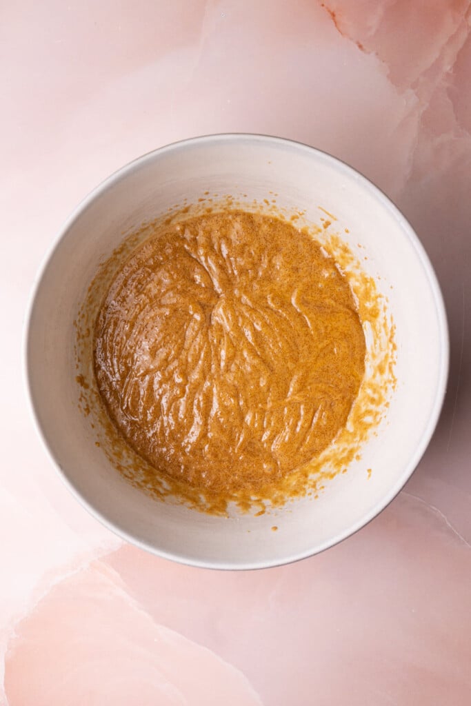 Sugar, oil, peanut butter, and eggs well-mixed together in a bowl. 