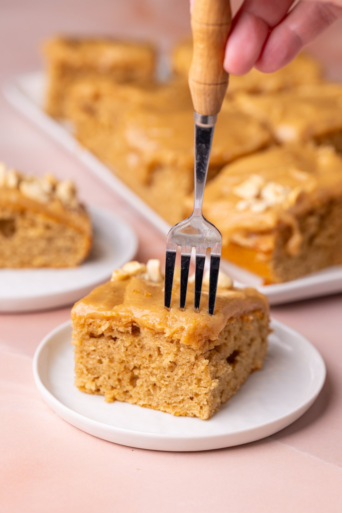 Putting fork through sheet cake with peanut butter to take a bite. 