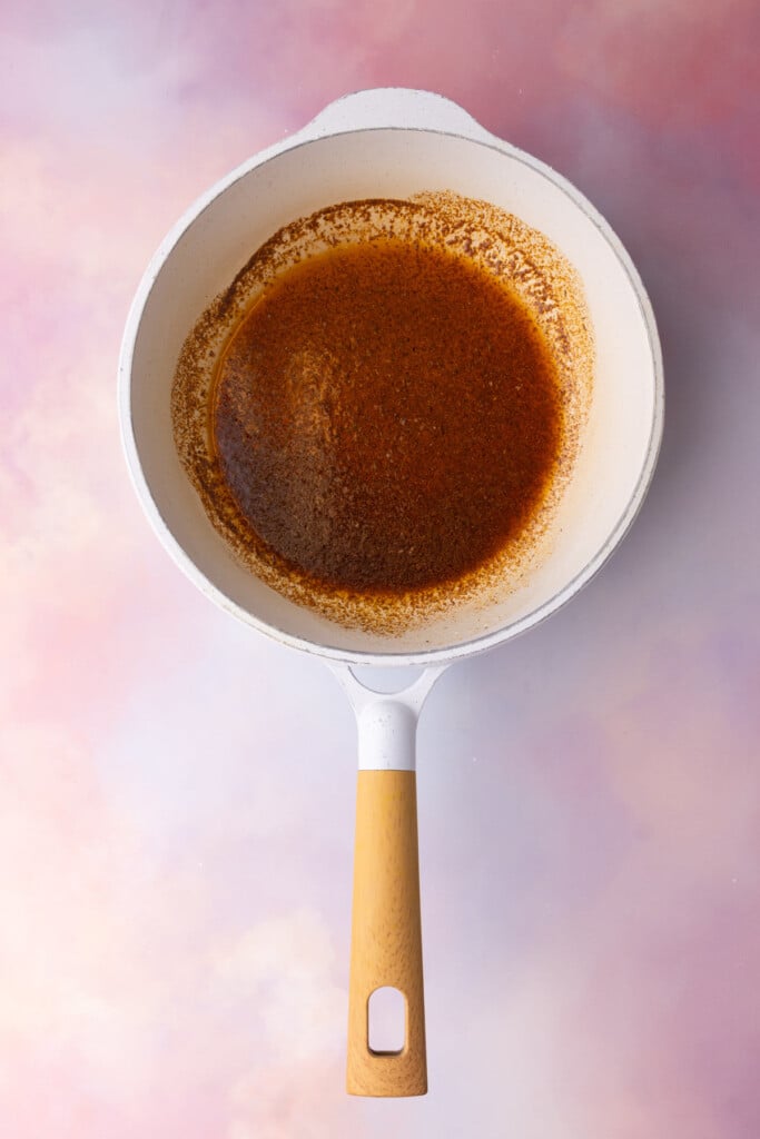 Melted butter with Cajun seasoning mixed into it in a pan.