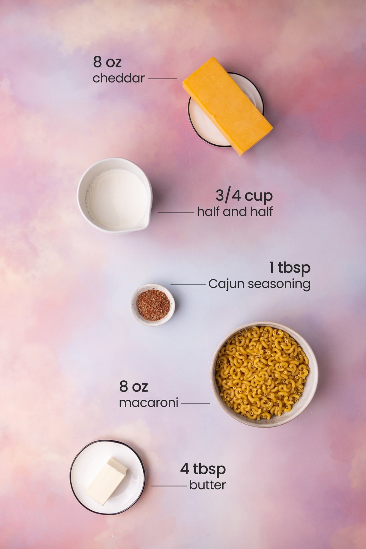Overhead view of all the ingredients for Cajun Mac and Cheese - cheddar, half and half, Cajun seasoning, macaroni, and butter.
