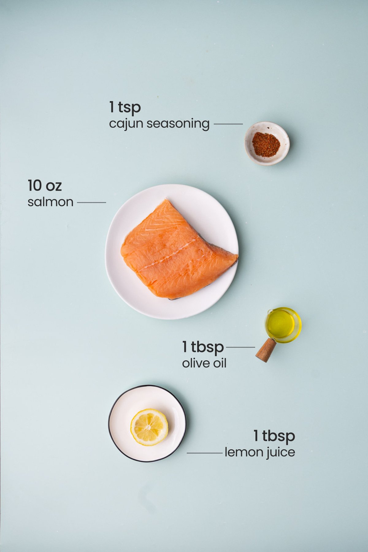 All ingredients needed for Cajun salmon including Cajun seasoning, salmon, olive oil, and lemon juice. 