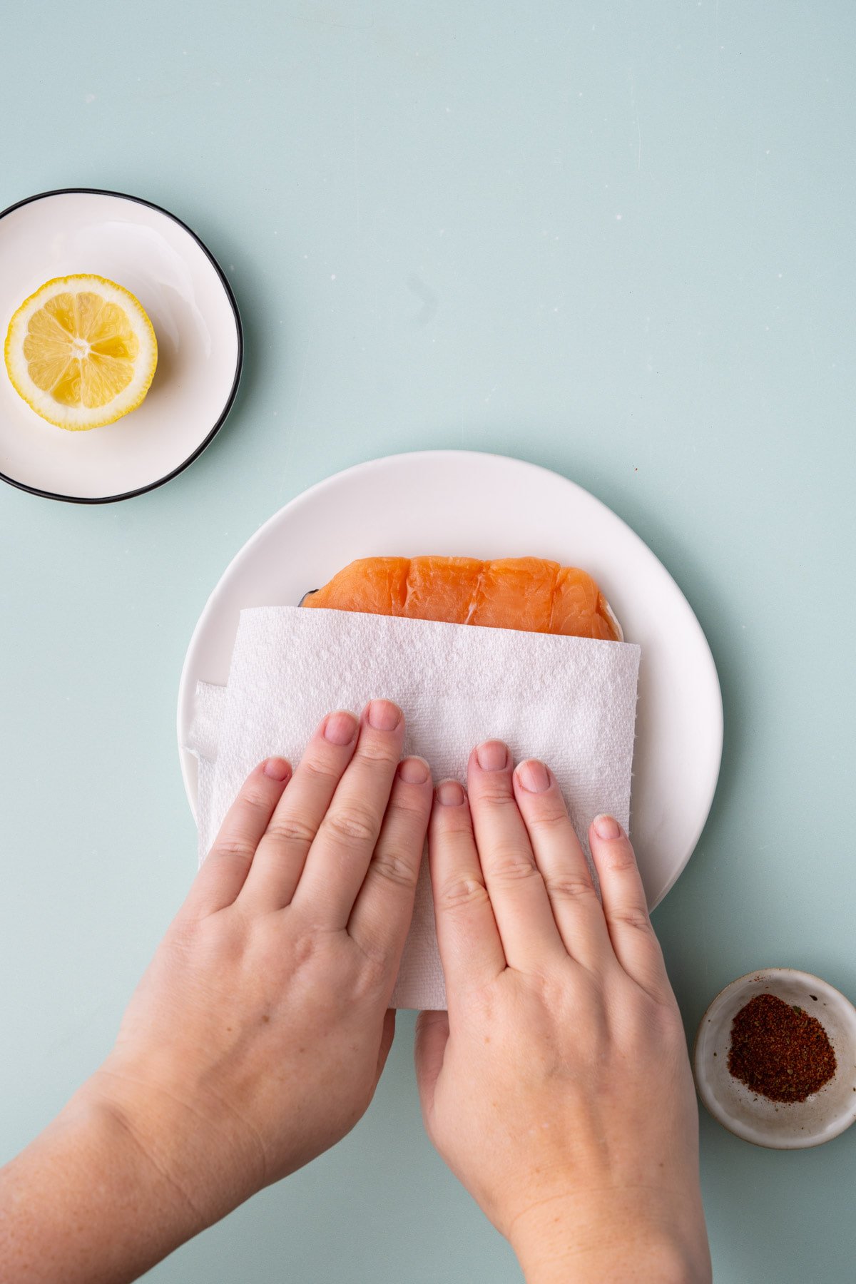 Patting salmon dry with paper towel to absorb any excess moisture.