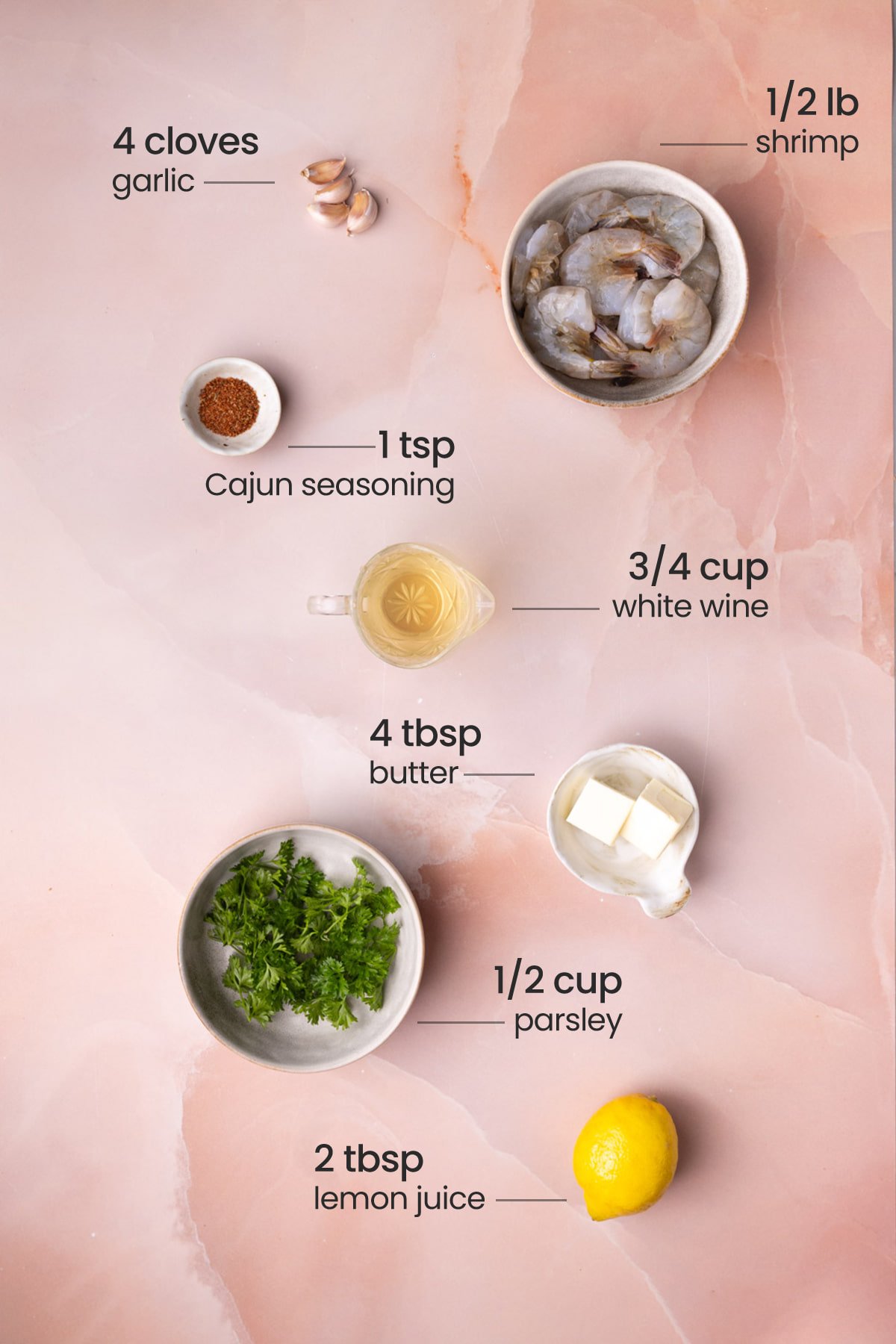 Everything you need for Cajun Shrimp Scampi including garlic, raw shrimp, Cajun seasoning, white wine, butter, parsley, and lemon.