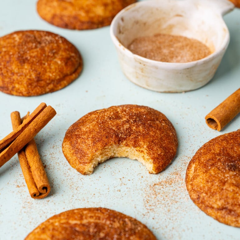 Soft snickerdoodles with the one in focus having a bite taken out of it to show the inside and the texture.