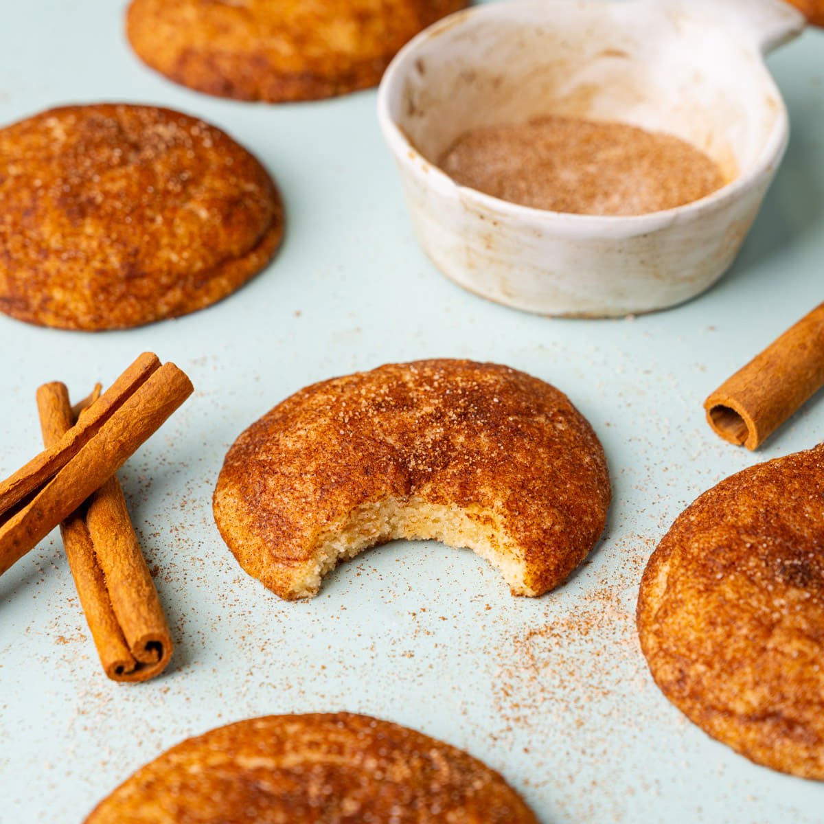 Soft snickerdoodles with the one in focus having a bite taken out of it to show the inside and the texture.