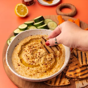 Dipping a piece of grilled pita into hot honey hummus.