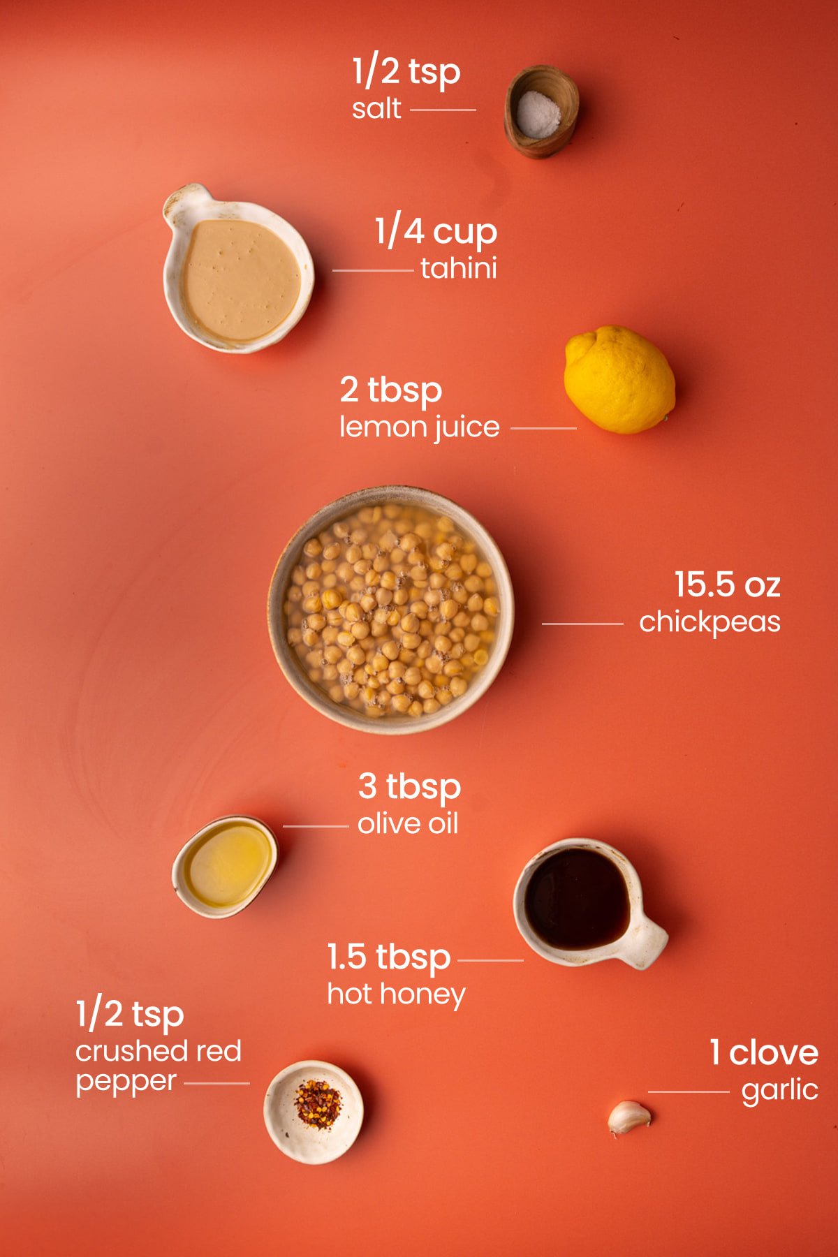 Everything you need to make hot honey hummus including salt, Tahini, lemon, chickpeas, olive oil, hot honey, and red pepper flakes. 