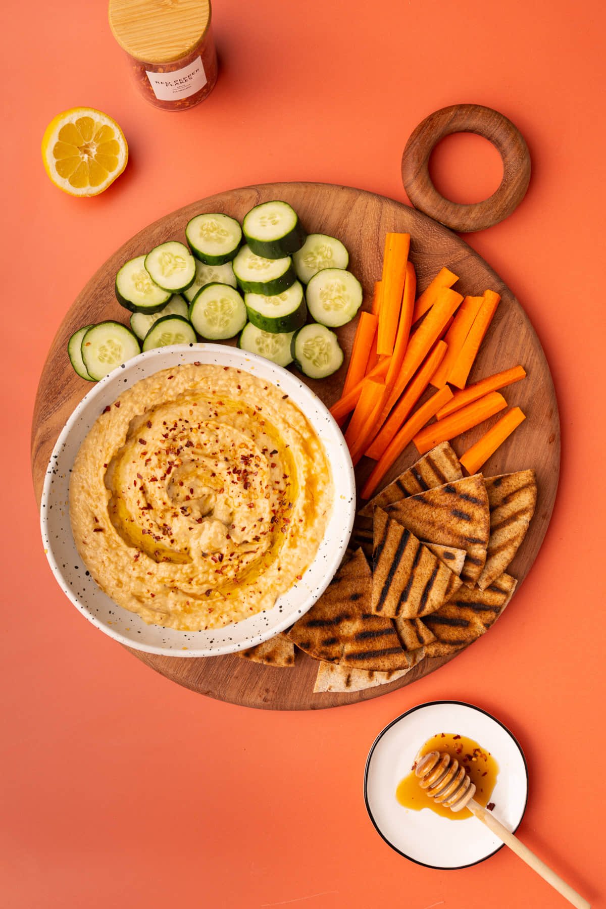 Grazing board with pita, veggies, and spicy hummus with hot honey in it. 