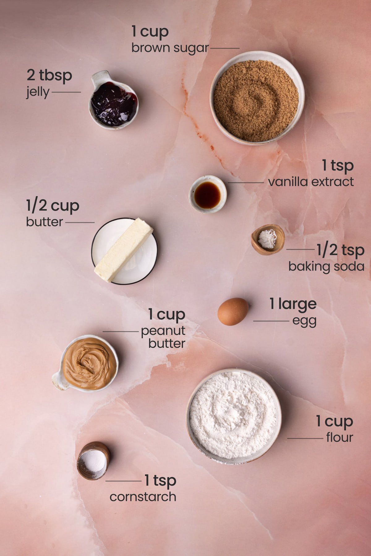 Everything you need for peanut butter and jelly cookies including jelly, peanut butter, vanilla extract, butter, cornstarch, egg, brown sugar, flour, and baking soda.