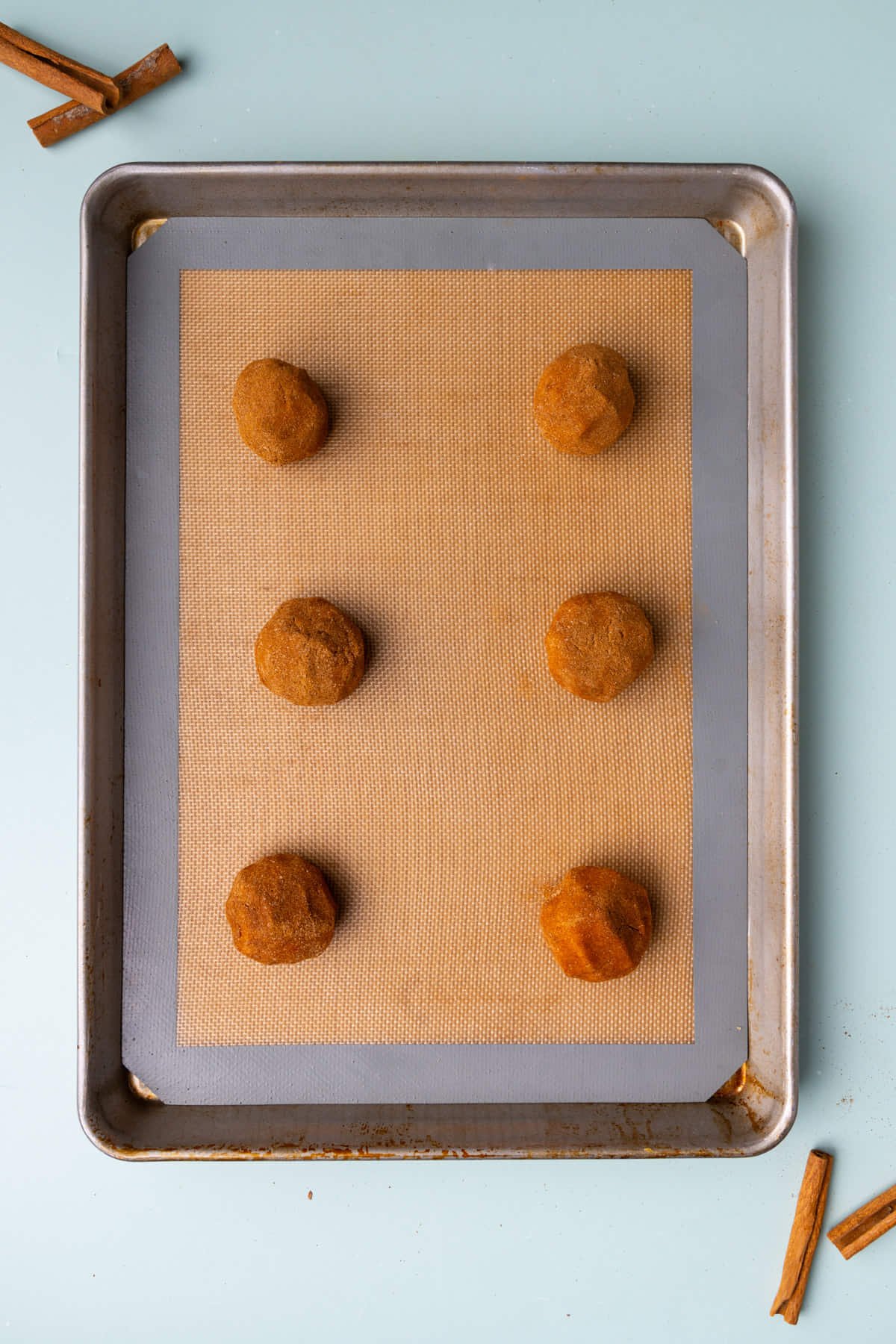 Snickerdoodles lined up on a baking sheet ready for the oven. 