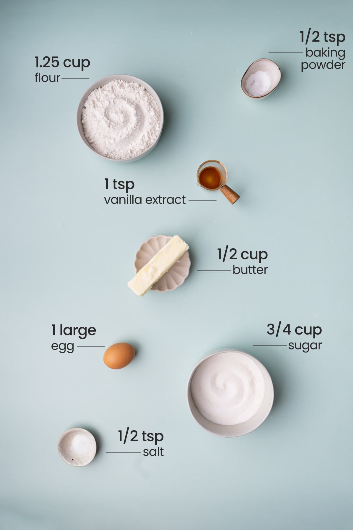Overhead view of ingredients needed for brown butter sugar cookies - flour, baking powder, vanilla extract, butter, egg, sugar, and salt.