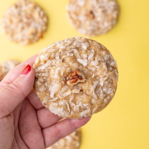 Holding a coconut pecan cookie up to the camera to show how much coconut is baked into the chewy cookie.