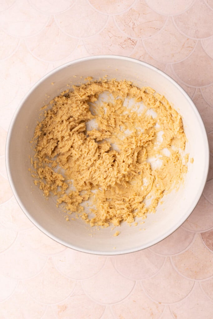 Brown sugar and softened unsalted butter creamed together in a large bowl for the base of chewy cookie dough. 
