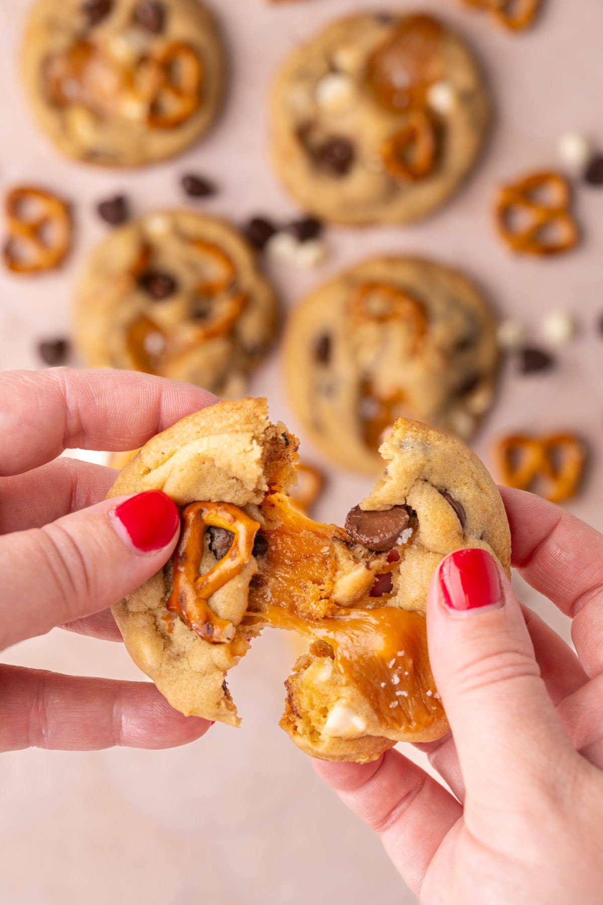 Pulling apart a kitchen sink cookie with gooey caramel stretching between two halves. 