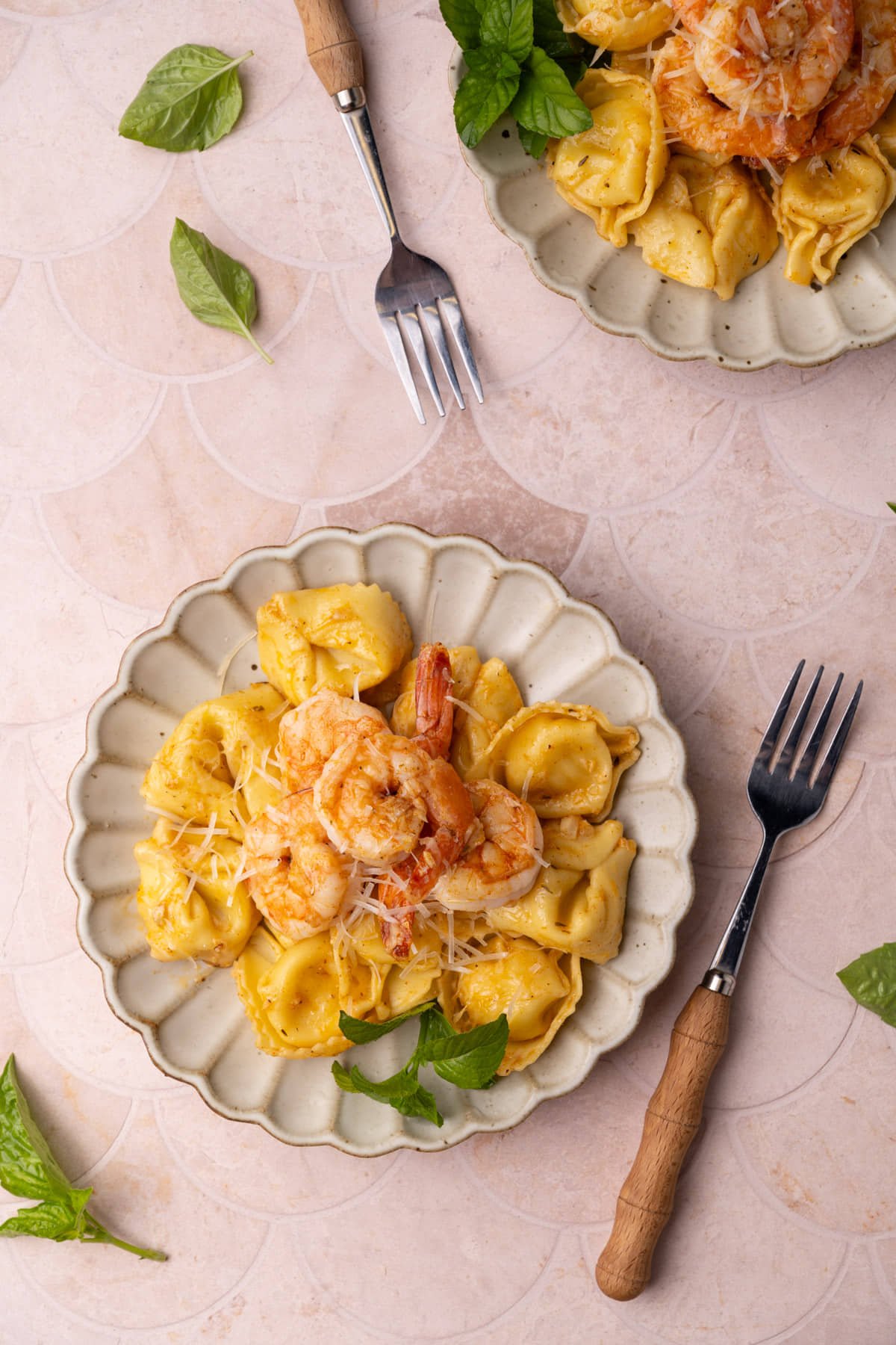 Overhead image of plated tortellini with shrimp garnished with fresh basil. 