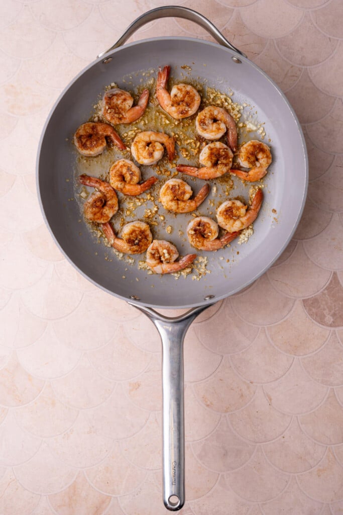 Cooking shrimp dusted with Cajun seasoning in simmering garlic and butter. 