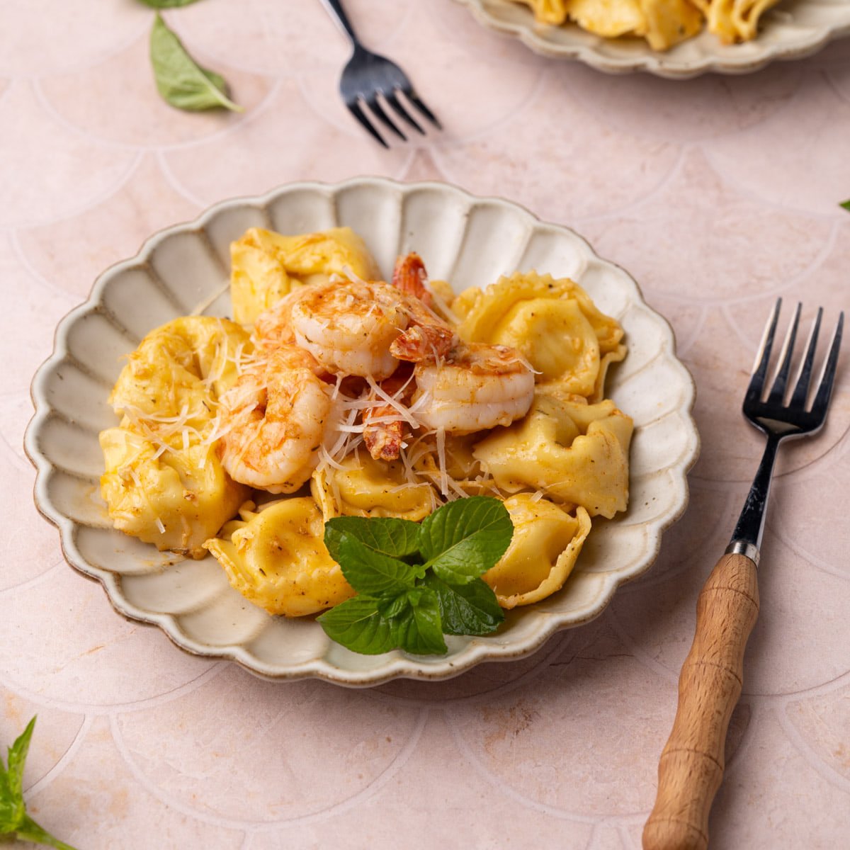 Petaled plate brimming with tortellini and Cajun shrimp and finished with grated Parmesan cheese and basil.