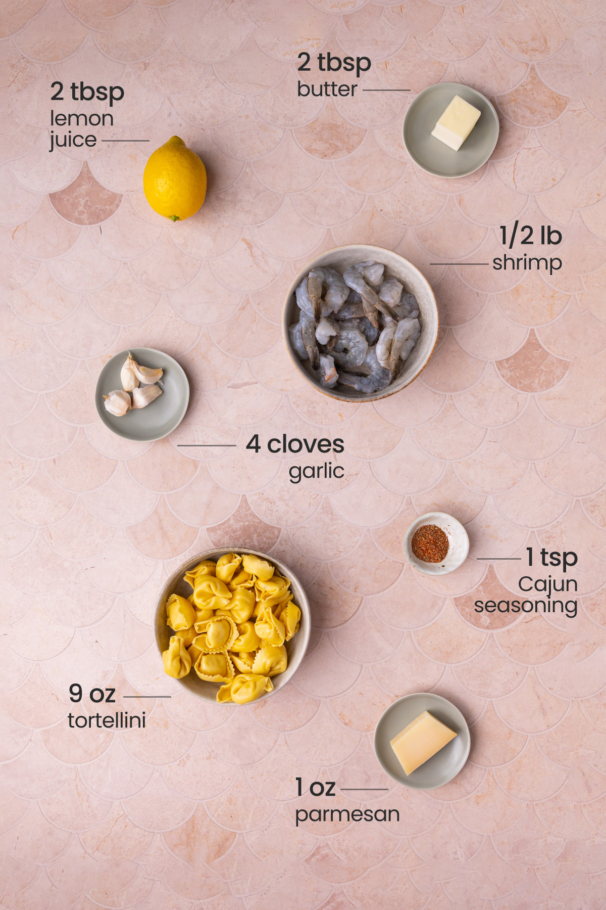 Overhead view of all the ingredients for shrimp tortellini - butter, lemon, shrimp, garlic, Cajun seasoning, tortellini, and parmesan.