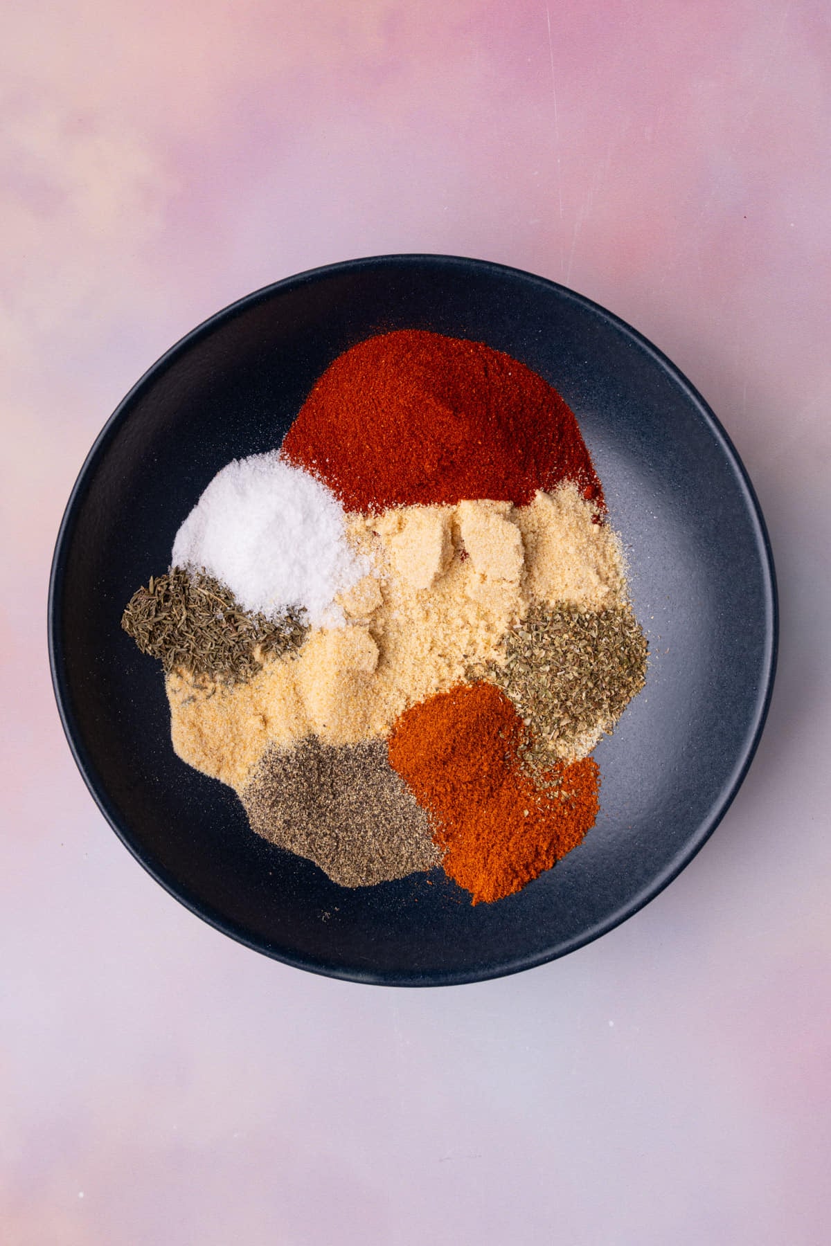 All the spices and herbs needed for homemade blackening seasoning in a shallow bowl.