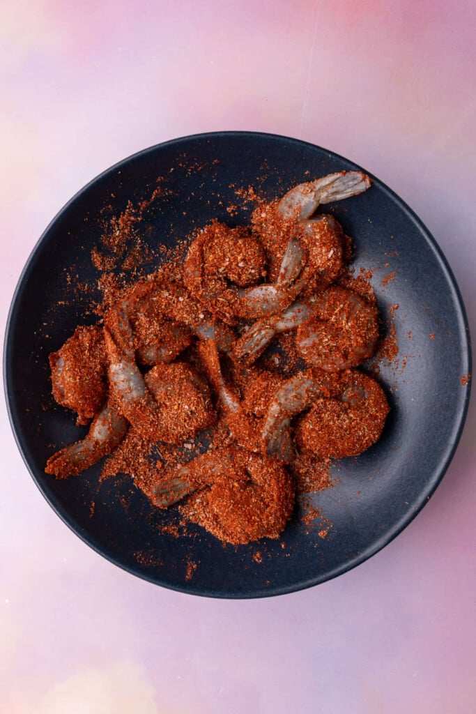 Coating shrimp generously in blackened seasoning.
