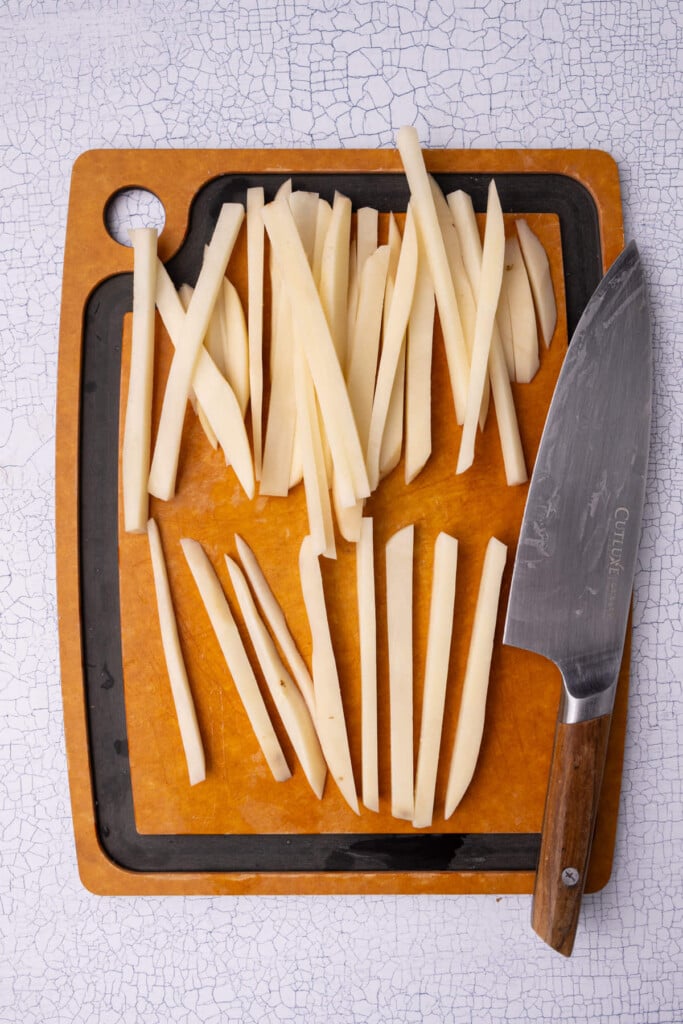 Cutting potatoes slices into strips to make fries.