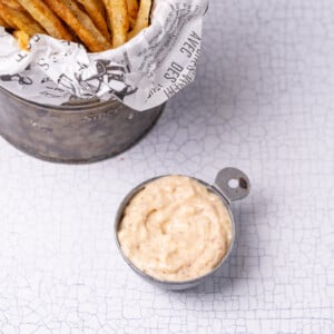 Spicy Cajun remoulade in a small pot served next to fries as a delicious dipping sauce.