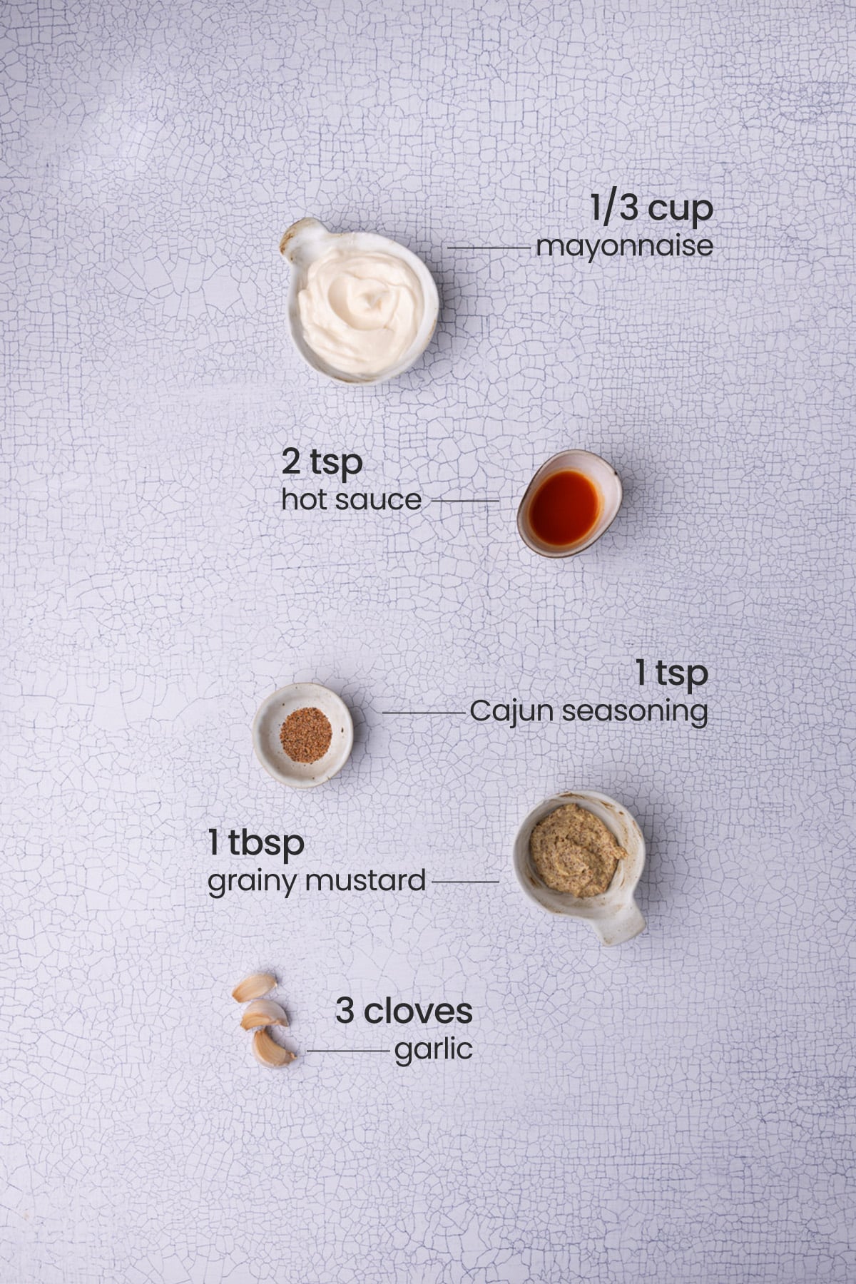 Ingredients for Cajun remoulade - mayonnaise, hot sauce, Cajun seasoning, grainy mustard, and garlic.