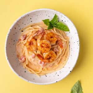Creamy Cajun Pasta topped with pan seared shrimp and garnished with fresh basil.