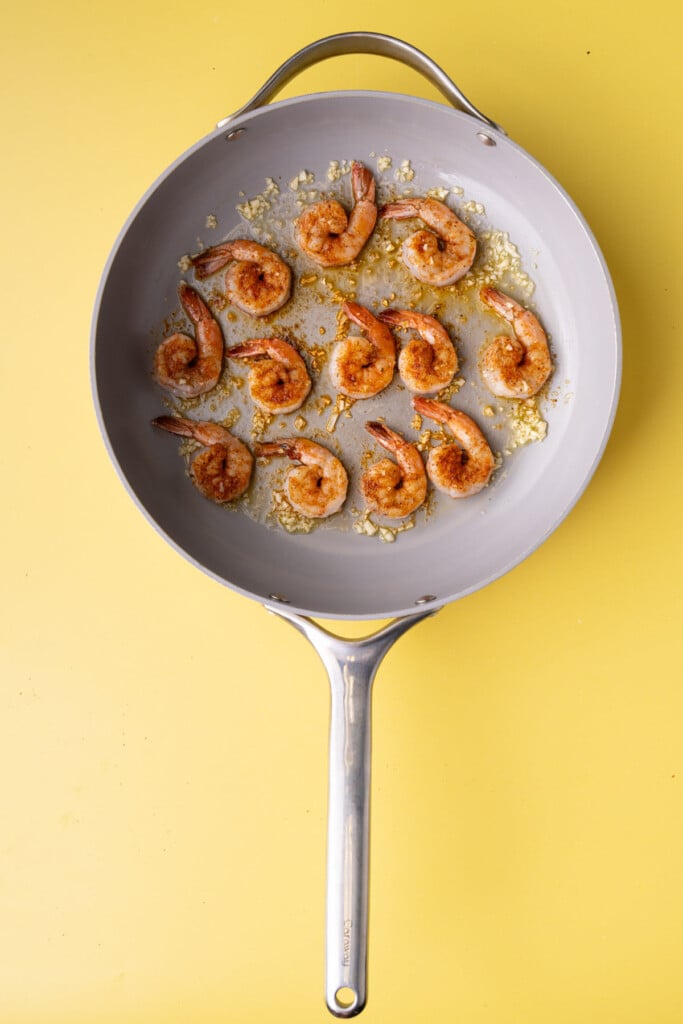 Shrimp with Cajun seasoning frying in olive oil and garlic.