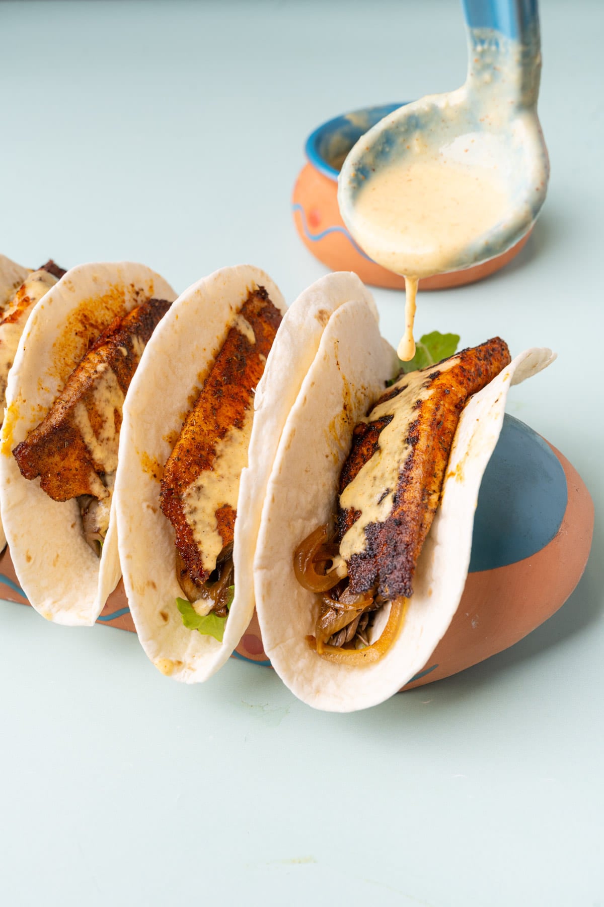 Dripping pineapple sauce over fish tacos.