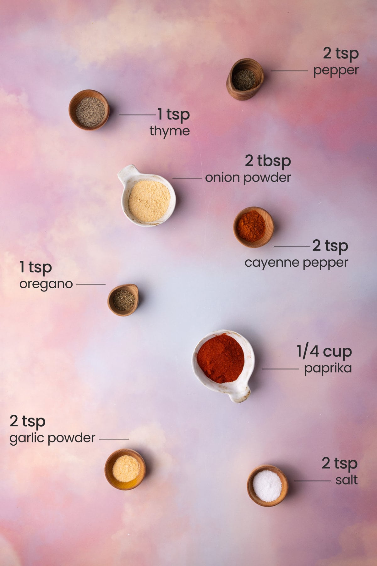 Overhead view of all the ingredients for homemade blackened seasoning - pepper, thyme, onion powder, cayenne pepper, oregano, paprika, garlic powder, and salt.