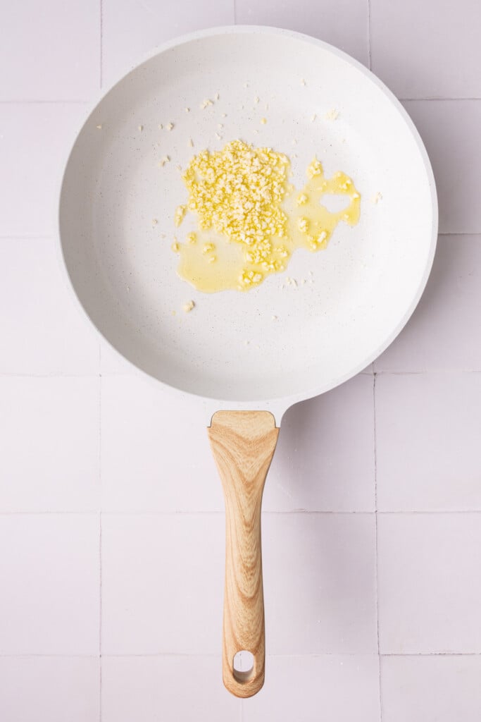 Minced garlic cooking in hot oil in a pan.