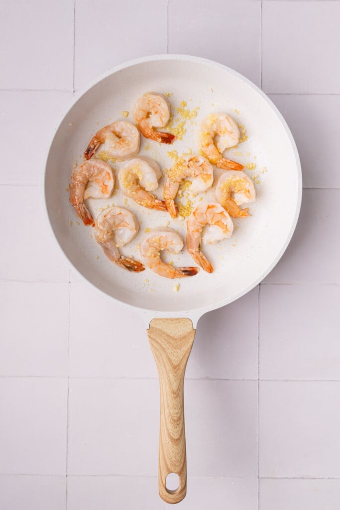 Cooking shrimp in hot oil and minced garlic for 2 minutes on each side.