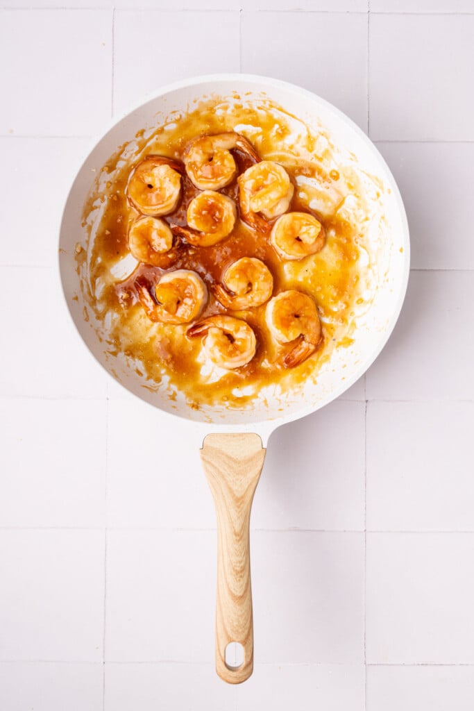 Shrimp cooking in honey garlic sauce that is actively thickening from cornstarch.