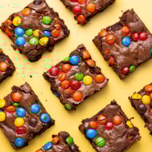 Colorful brownies with M&M's lined up on a yellow background.