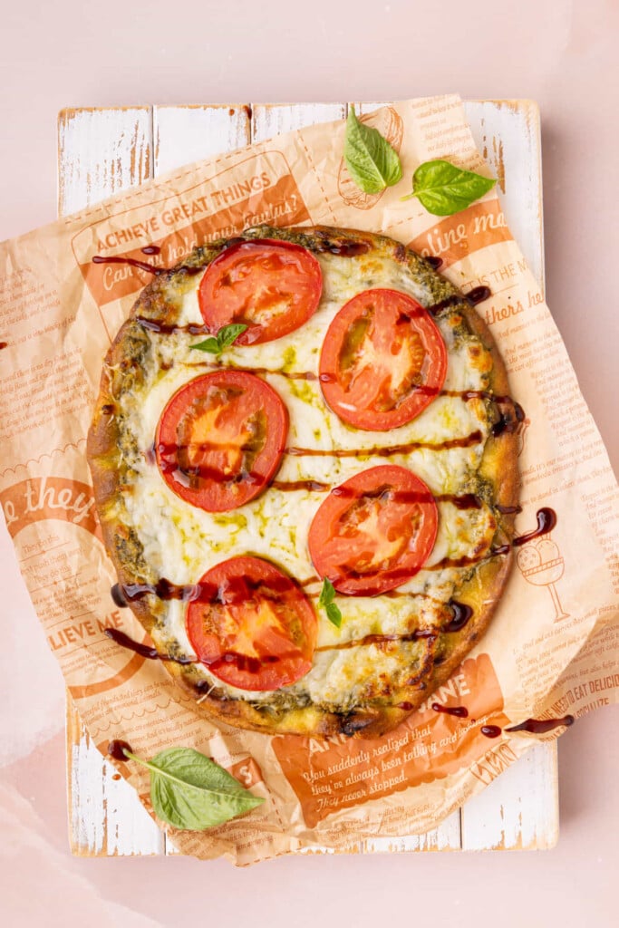Balsamic glaze drizzle over pesto pizza on naan bread with fresh tomatoes.