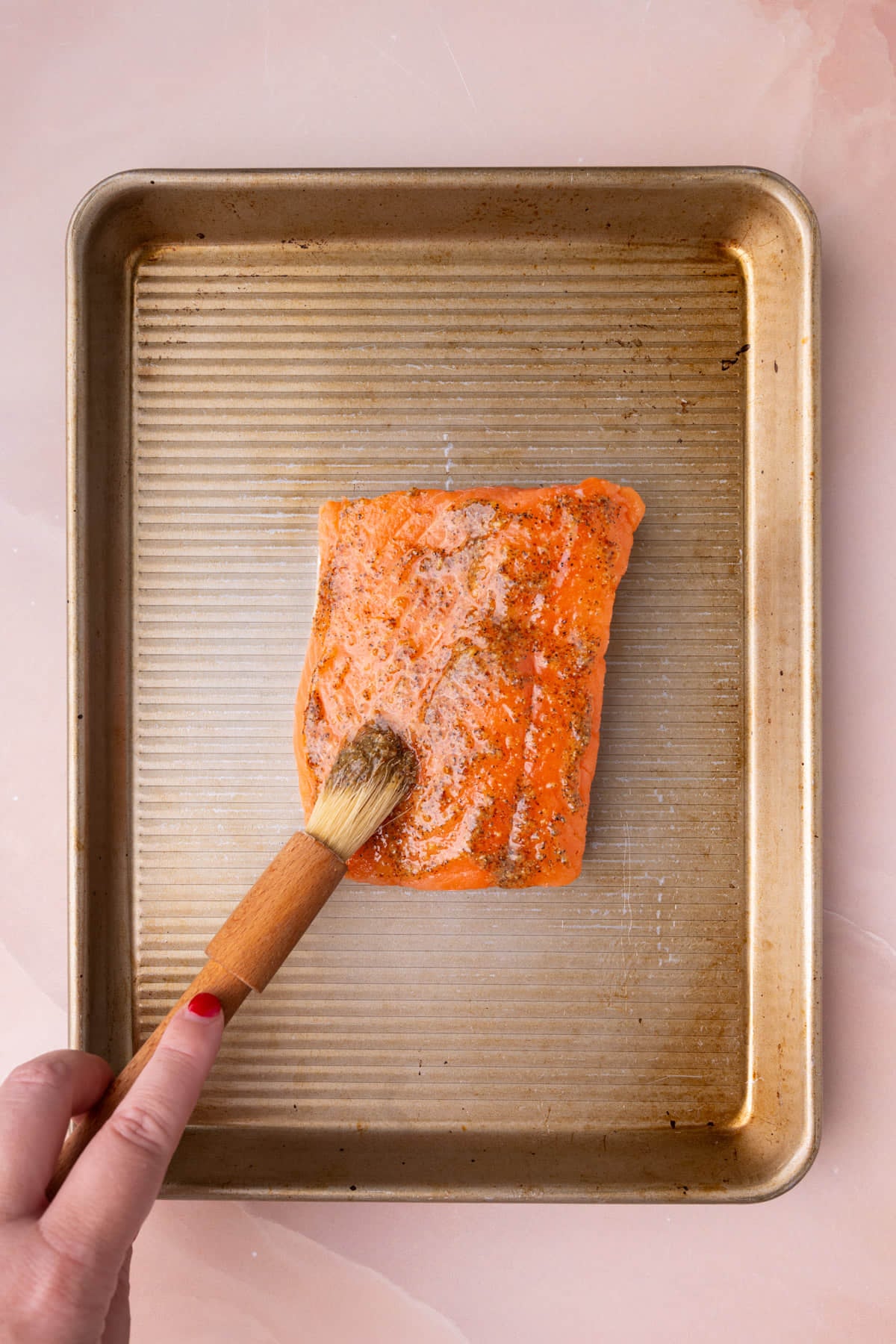 Brushing raw salmon with honey mustard marinade.