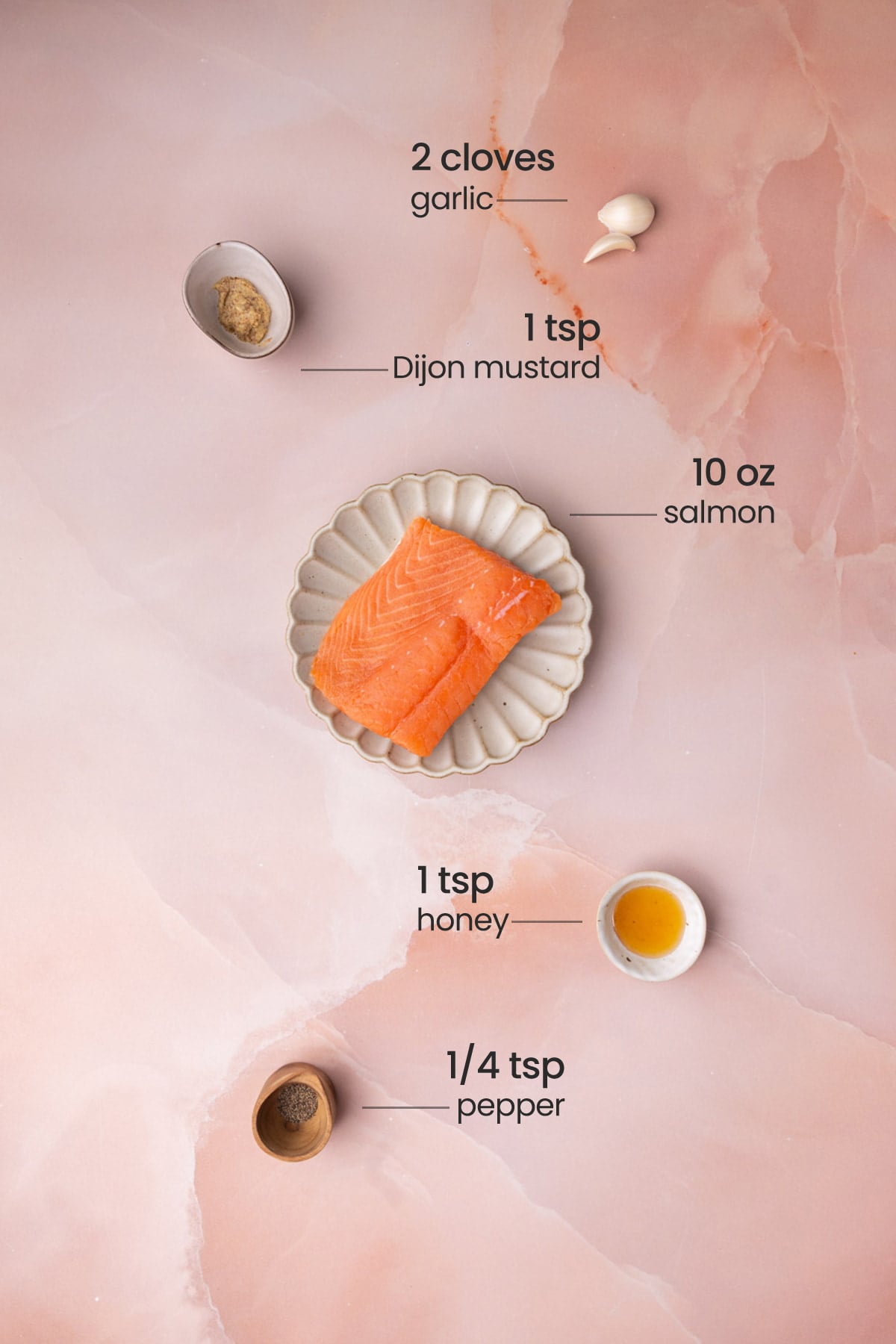 Overhead view of all ingredients for honey mustard salmon - garlic, Dijon mustard, salmon, honey, and pepper.