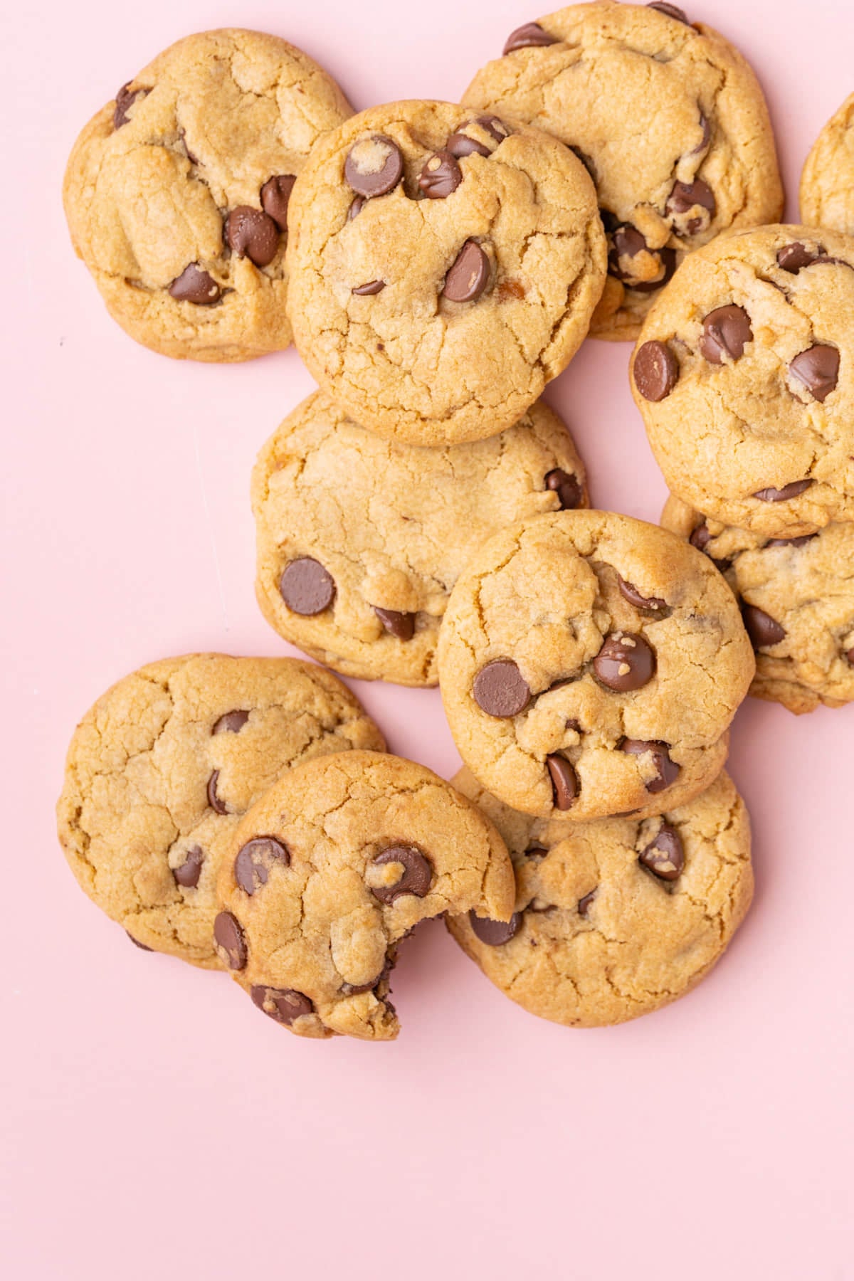 Cookies placed sporadically on a pink background, one with a bite taken out of it.